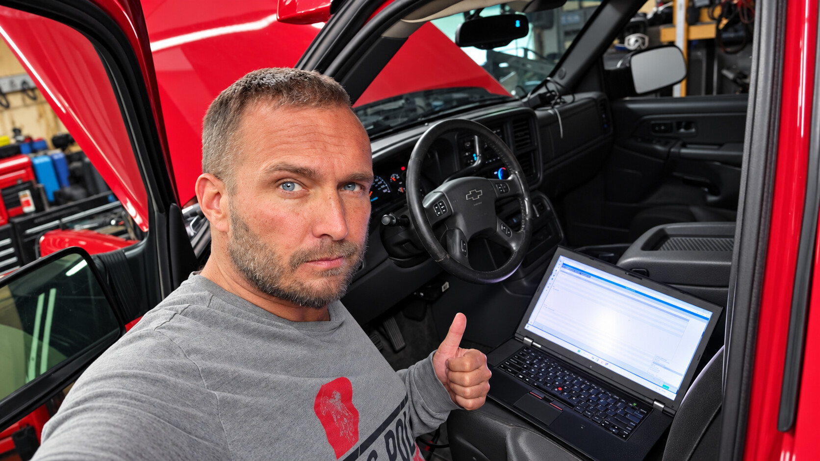 Mike Delaney performing vehicle diagnostics with a laptop inside a Chevrolet truck